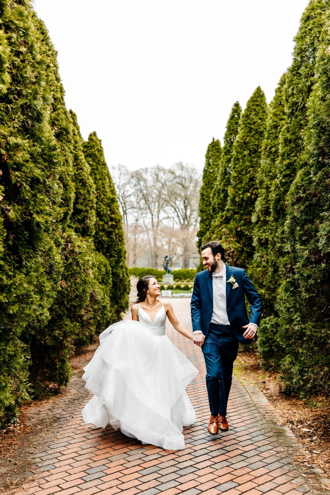 Memphis wedding photographer captures bride and groom running through Memphis Botanic Garden while laughing